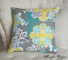 a white couch with a gray and yellow flowered pillow on it's back