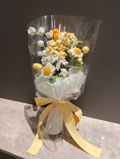 a bouquet of yellow and white flowers wrapped in plastic