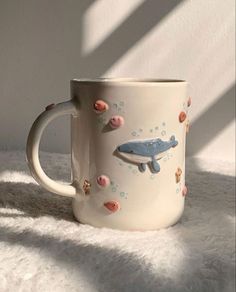 a coffee mug with an image of a whale and fish on the inside is sitting on a fluffy white surface