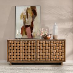 a painting and vase sitting on top of a wooden cabinet in front of a wall