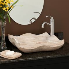 a bathroom sink sitting next to a vase with yellow flowers in it and a mirror on the wall