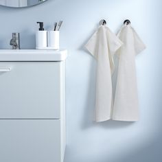 two white towels hanging on the wall next to a sink