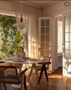 a table and chairs in a room with plants on the windowsills, near a door