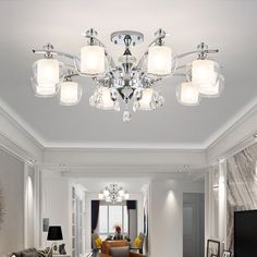 a living room filled with furniture and a chandelier hanging from the middle of it