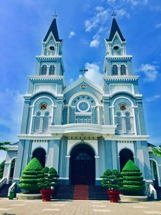 a large white church with two steeples on it's sides and trees in the front