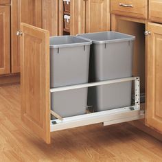 two gray trash cans sitting on top of a wooden cabinet