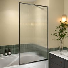 a bathroom with two sinks and a bathtub next to a plant in a vase