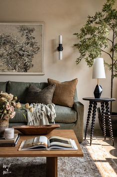 a living room filled with furniture and flowers on top of a coffee table in front of a painting