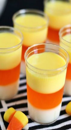 small glasses filled with candy corn puddings on a black and white striped tablecloth