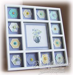 an altered picture frame with paper flowers and pictures on the inside is decorated in blue and white