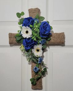 a cross decorated with blue flowers and greenery hangs on the front door to welcome guests