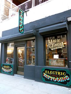 an electric tattoo shop with neon signs on the side of it's storefront