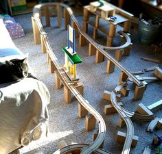 a cat laying on top of a bed next to a toy train set and track