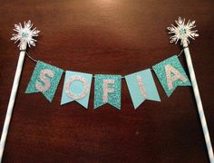 a cake topper that says sofia on it with snowflakes hanging from the side