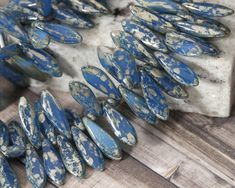 some blue and white beads are on a table next to a piece of wood that has been cut into smaller pieces