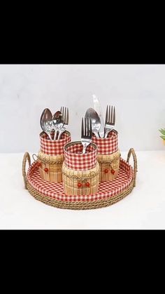 three forks and two knives in a basket with red checkered napkins on it