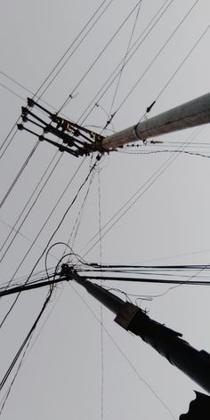 an overhead view of power lines and wires against a gray sky with only one telephone pole visible