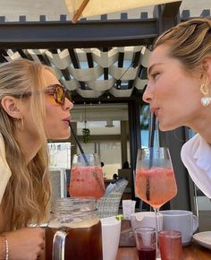 two beautiful women sitting at a table with drinks