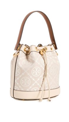 PRICES MAY VARY. Fabric: Jacquard Structured silhouette, Gold-tone hardware, Monogram pattern, Leather trim Length: 8.25in / 21cm, Height: 8.25in / 21cm, Handle drop: 4in / 10cm, Strap drop: 21.75in / 55cm, Depth: 4.75in / 12cm Drawstring top Patch interior pocket A scaled-down Tory Burch bucket bag, detailed with a rendition of the label's monogram for a polished and eye-catching look. Two shades of leather trim lend an eclectic finish to the silhouette. Tory Burch Bucket Bag, T Monogram, Mini Bucket Bags, Mini Bucket, Monogram Pattern, Drawstring Top, Tory Burch Bag, Color Ivory, Free Bag