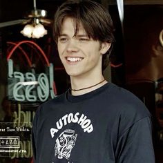 a young man standing in front of a store window