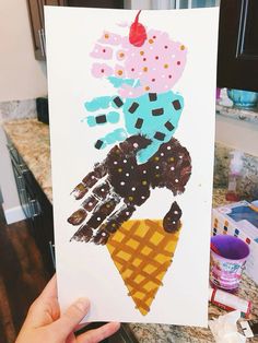 a hand holding up a piece of paper with ice cream and chocolate sprinkles on it