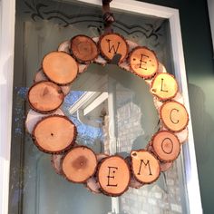 a wreath made out of wood with the word welcome written on it in front of a door