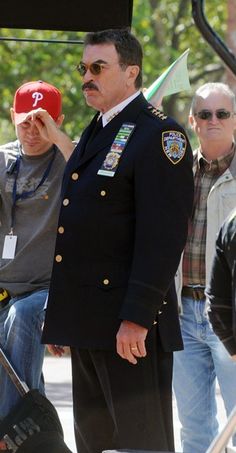 a man in uniform standing next to other men and one is holding a red hat