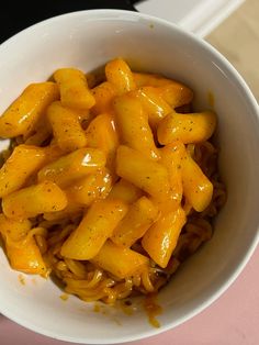 a white bowl filled with macaroni and cheese on top of a pink table