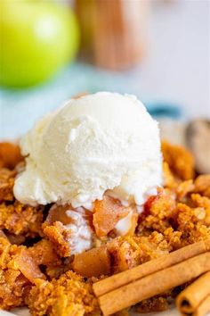 an apple crisp dessert with ice cream on top and cinnamon sticks in the foreground