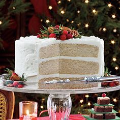 a white cake sitting on top of a glass platter next to a christmas tree