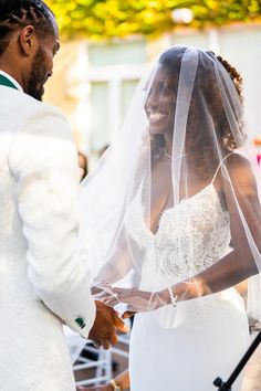 the bride and groom are smiling as they hold hands during their wedding ceremony in front of an audience