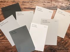 five different shades of gray paint sitting on top of a wooden table next to each other