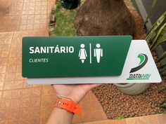 a person holding up a green and white sign that says sanitario clavetes