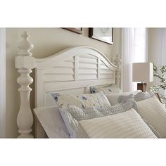 a bed with white headboard and pillows on top of it next to a window