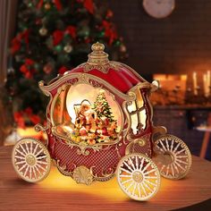 a red and gold carriage with a christmas tree in the back on a wooden table