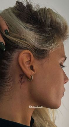 a woman with a small flower tattoo on her ear