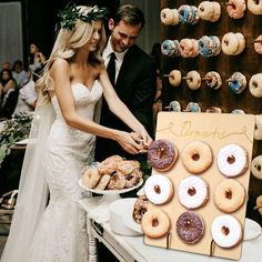 a bride and groom are cutting their wedding cake with doughnuts on the table