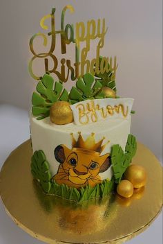 a lion themed birthday cake on a gold platter with greenery and fruit around it