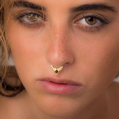 a woman with a nose piercing in her left eye and gold jewelry on her right side