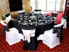 a table with black and white polka dots on the chair covers is set up for a formal function