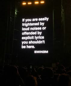 a large screen with words on it in the middle of a dark room at an event