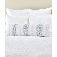 a white bed topped with pillows and blankets