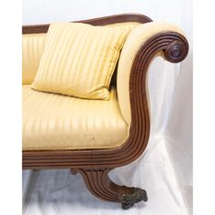 an old fashioned chair with two pillows on it's back and arm rests against a white backdrop