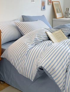 a bed with blue and white striped comforter next to a nightstand in a bedroom