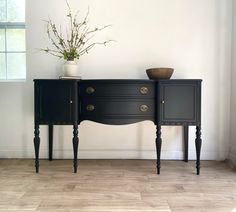 a black sideboard with two drawers and a potted plant sitting on top of it