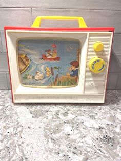 an old tv sitting on top of a counter next to a yellow and red object