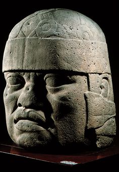 an ancient mask is on display in a museum case, with the image of a man's face carved into it