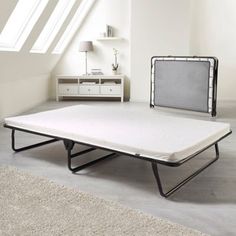 a white bed frame sitting on top of a floor next to a dresser and lamp