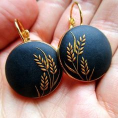 a pair of black and gold earrings with leaves on them