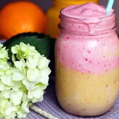 there is a pink drink in a mason jar next to some flowers and oranges